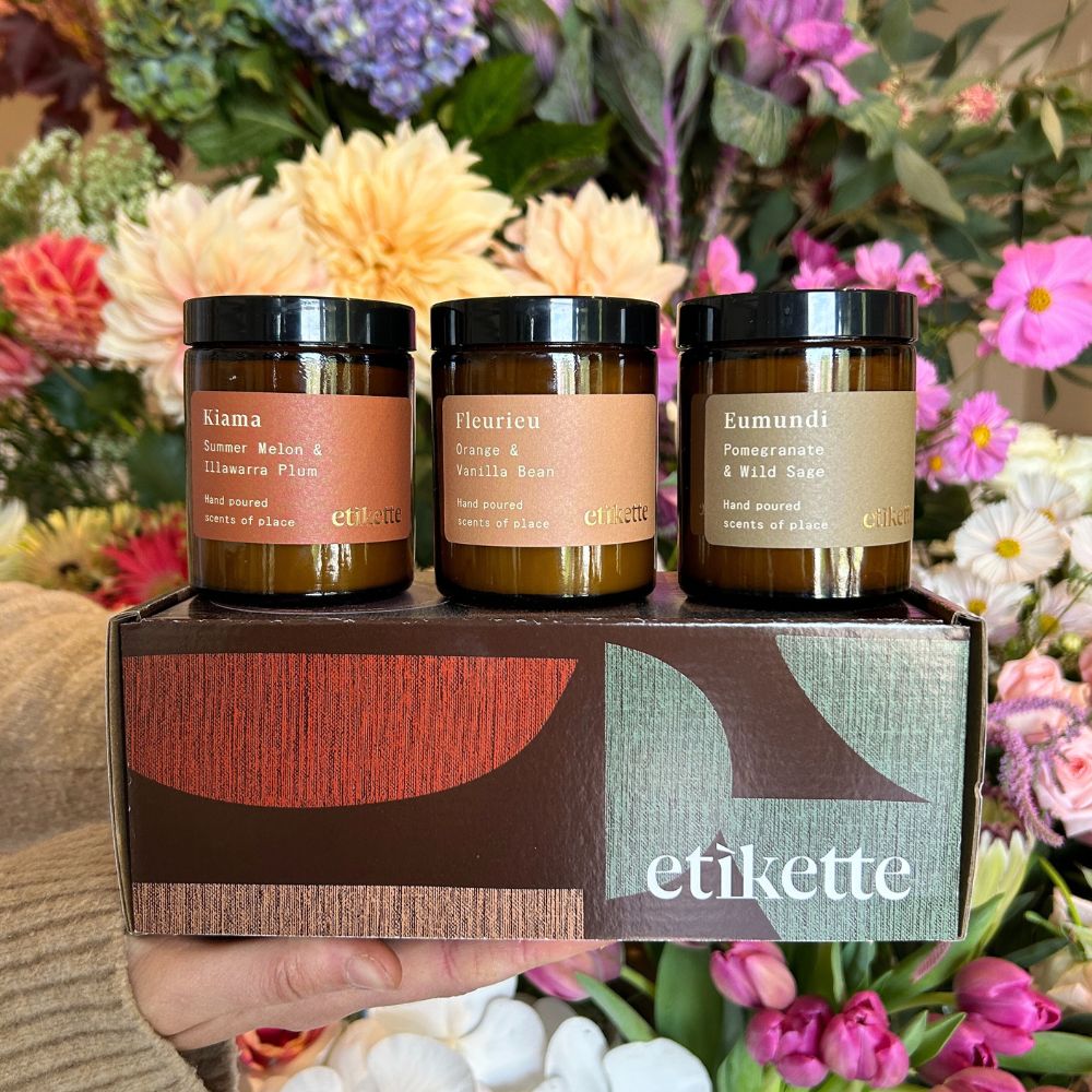 trio of etikette candles gift box in front of flowers