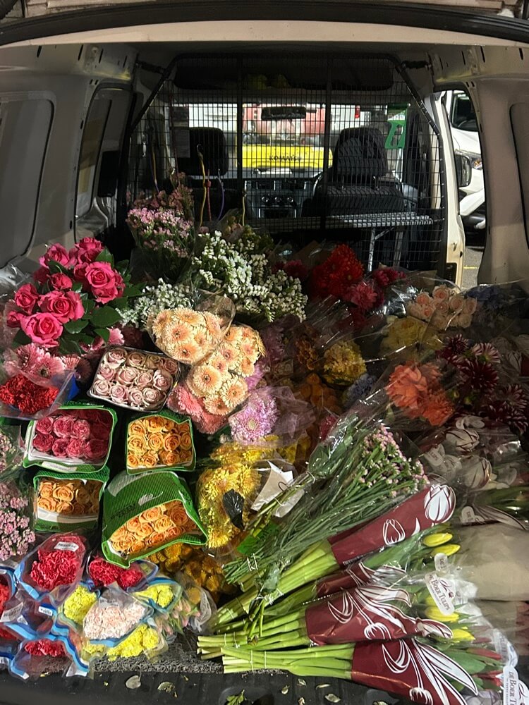 Back of a van filled with various bouquets of flowers.
